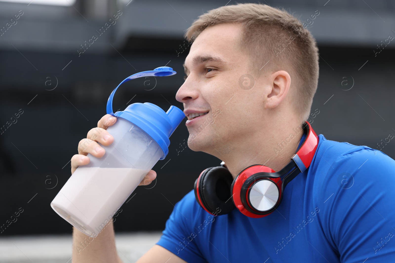 Photo of Smiling athletic man drinking protein shake outdoors