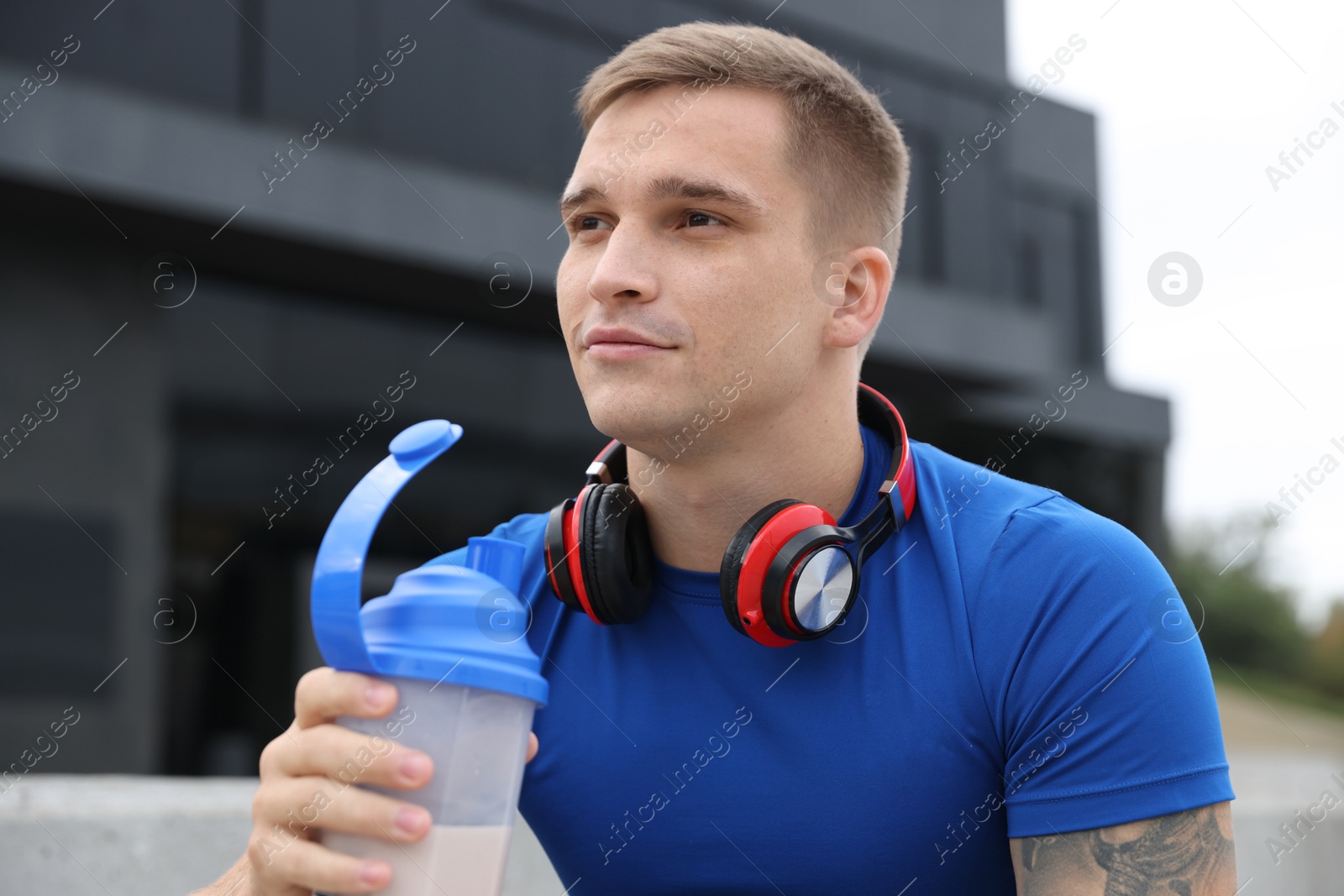 Photo of Athletic man with shaker of protein drink outdoors