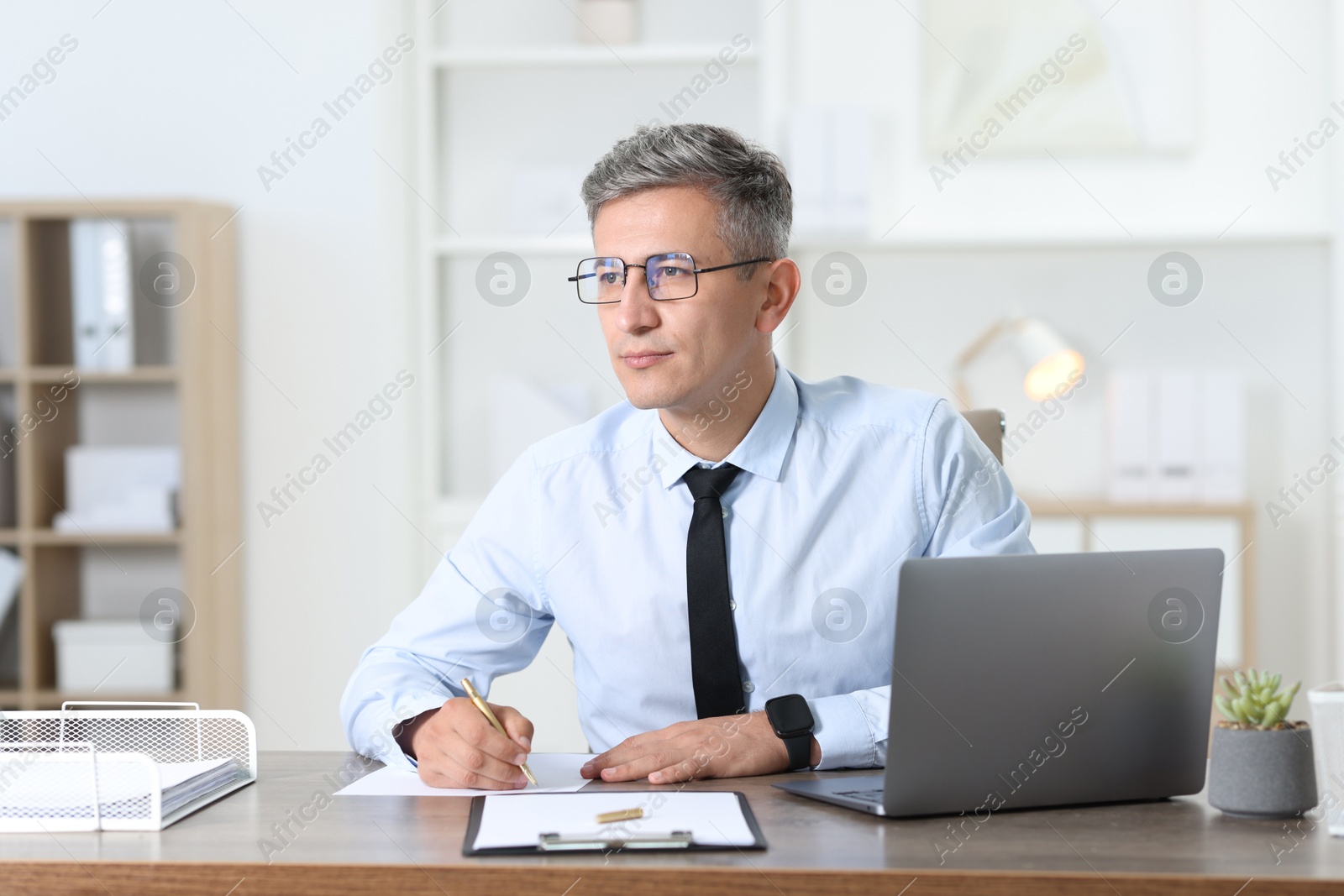 Photo of Businessman taking notes at table in office