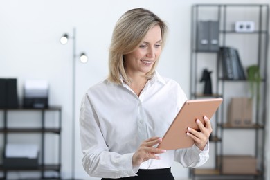 Portrait of happy businesswoman using tablet in office