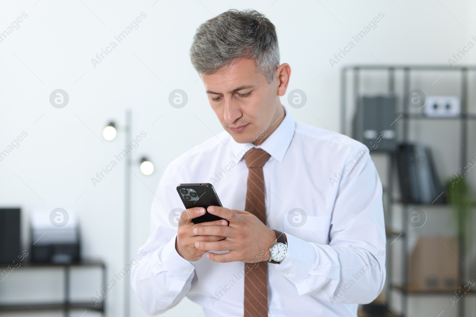 Photo of Portrait of businessman using smartphone in office