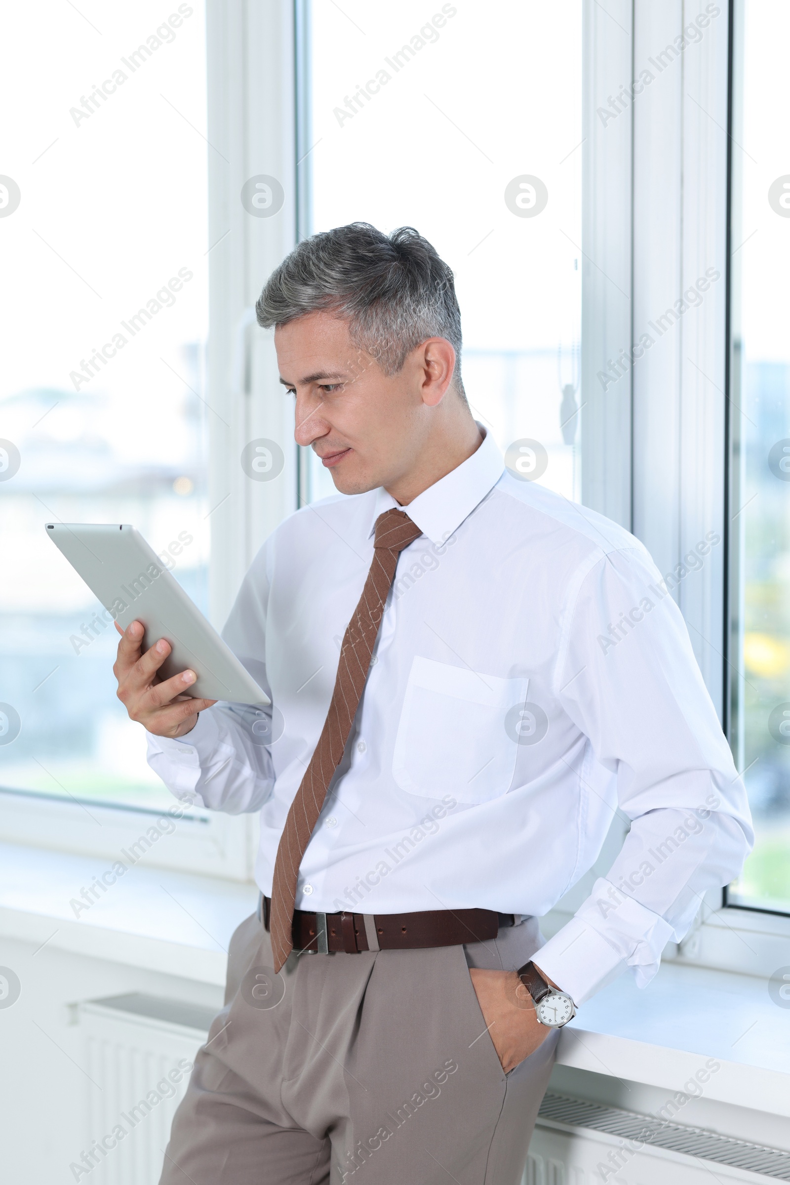 Photo of Businessman using tablet near window in office