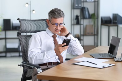 Photo of Businessman using smartphone at table in office