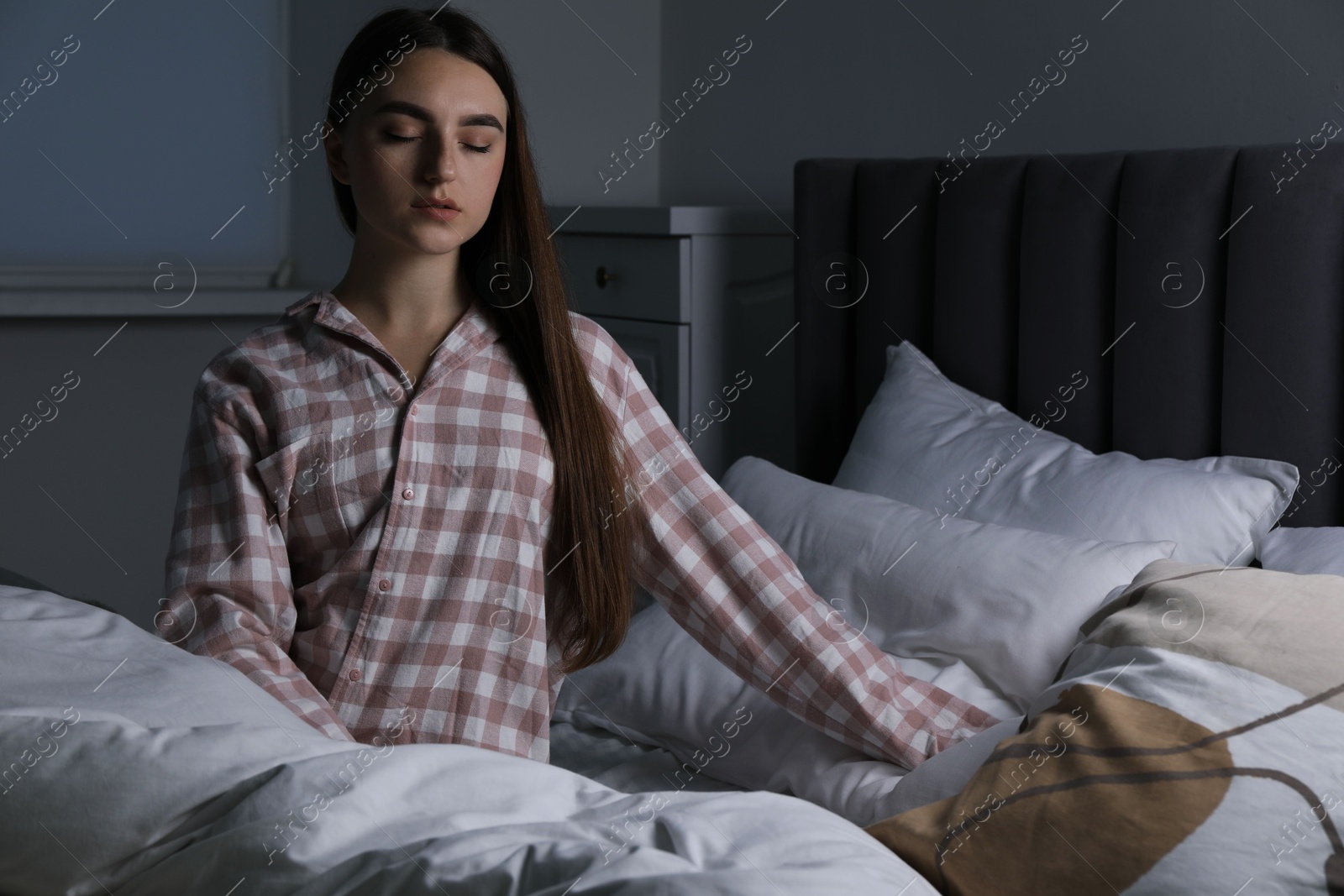 Photo of Young woman suffering from sleepwalking on bed at home