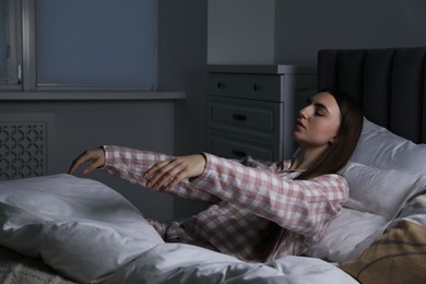 Photo of Young woman suffering from sleepwalking on bed at home