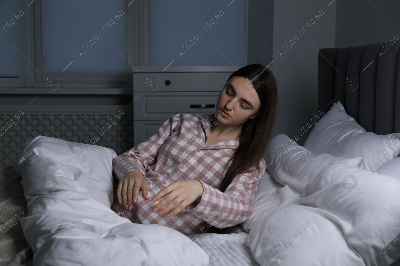 Photo of Young woman suffering from sleepwalking on bed at home