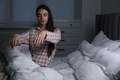 Photo of Young woman suffering from sleepwalking on bed at home