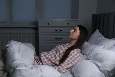 Photo of Young woman suffering from sleepwalking on bed at home