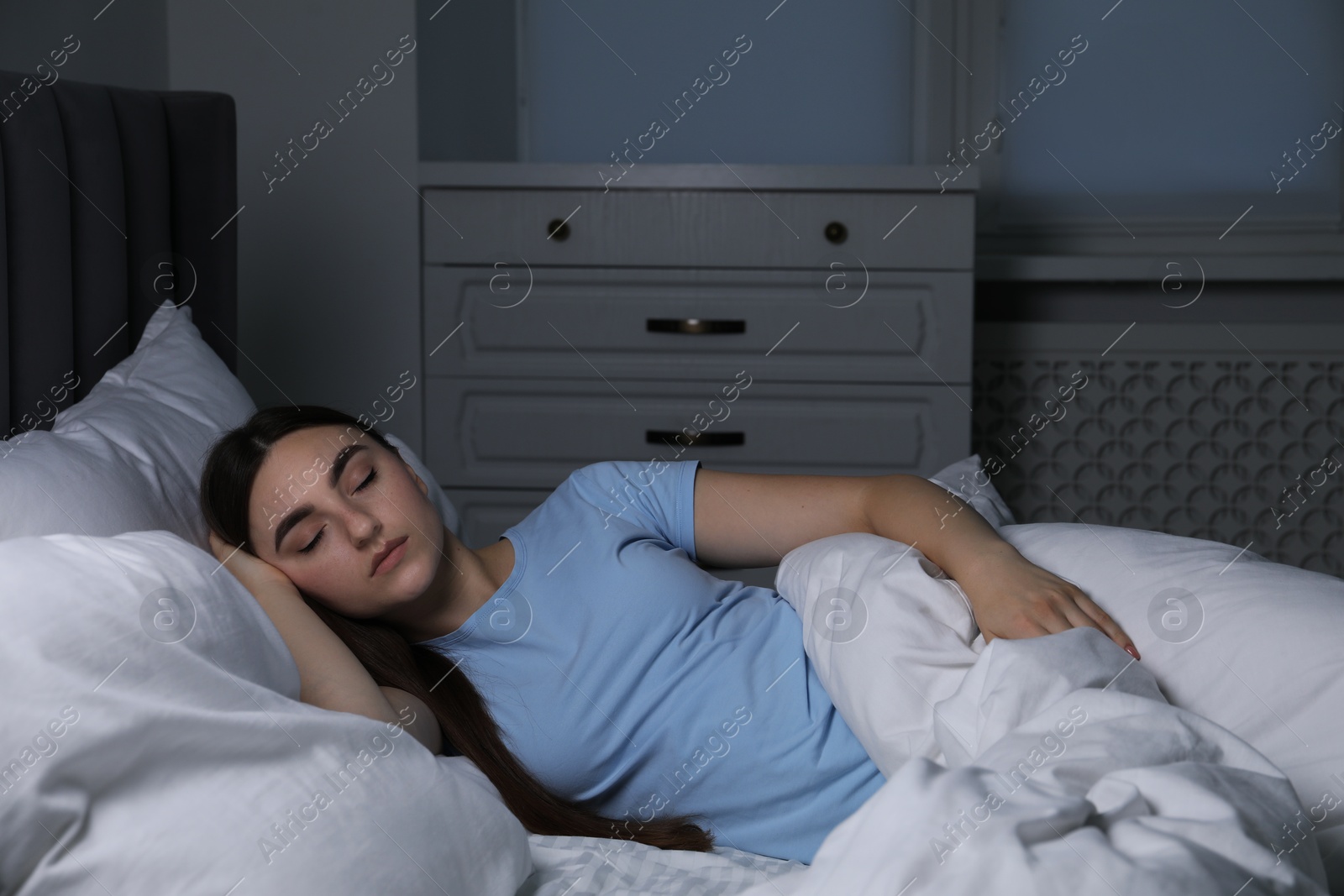 Photo of Young woman sleeping in soft bed at night