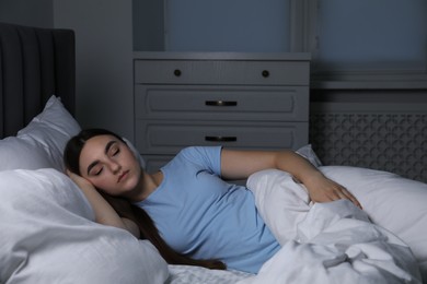 Photo of Young woman sleeping in soft bed at night