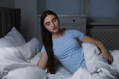 Photo of Young woman suffering from sleepwalking on bed at home