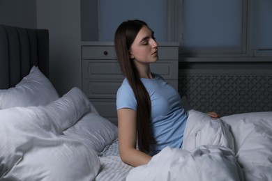 Photo of Young woman suffering from sleepwalking on bed at home