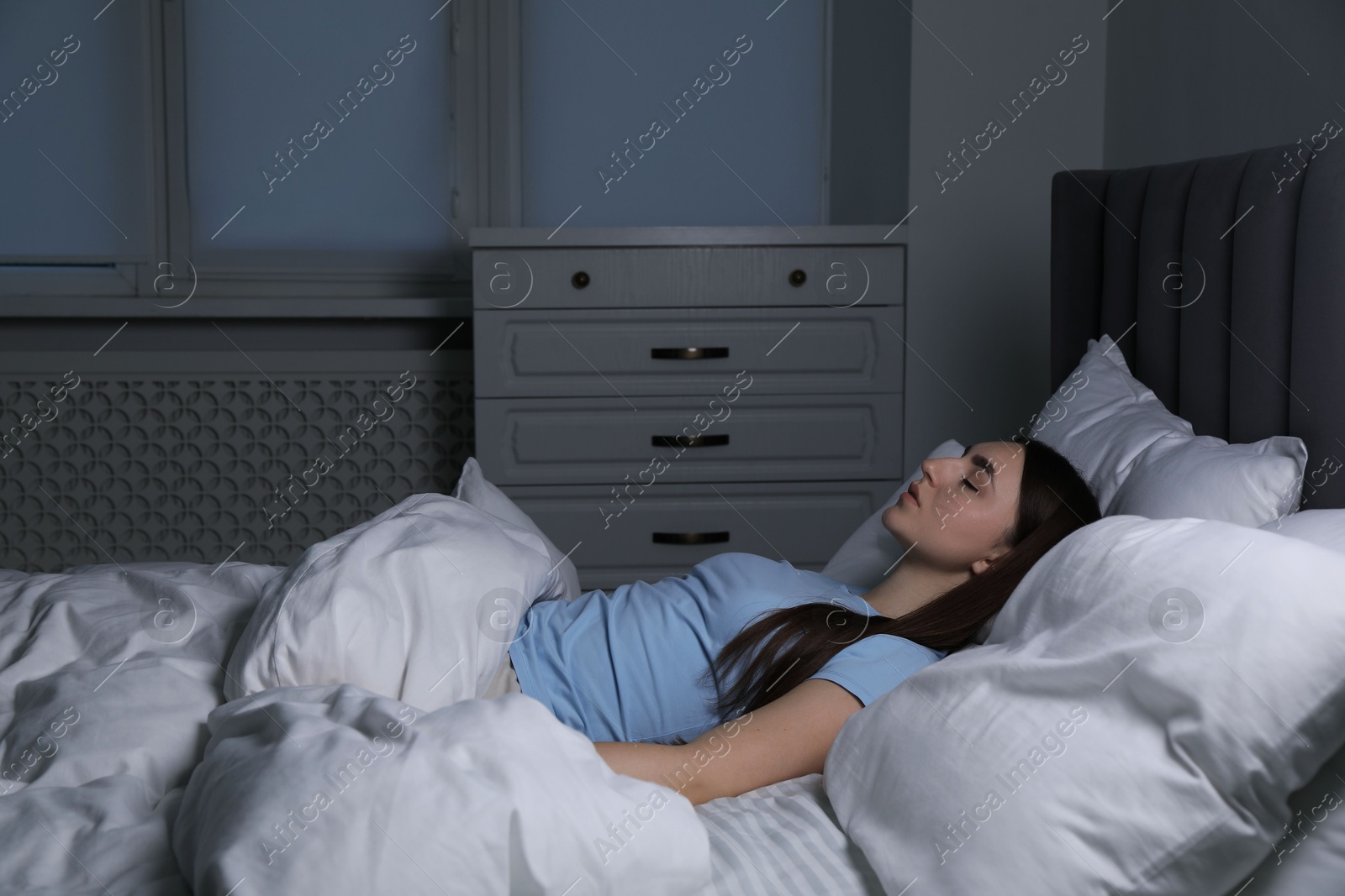 Photo of Young woman sleeping in soft bed at night