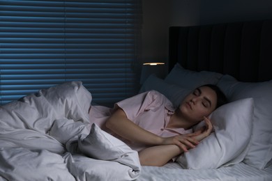 Photo of Young woman sleeping in soft bed at night