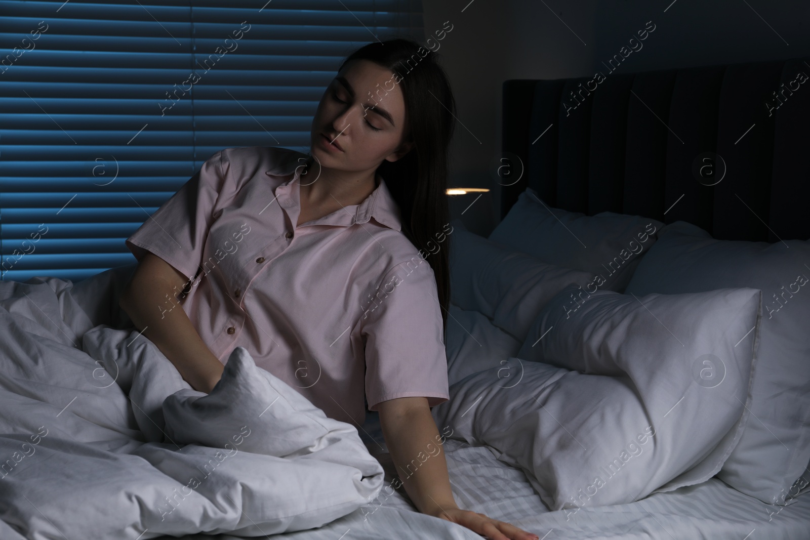 Photo of Young woman suffering from sleepwalking on bed at home