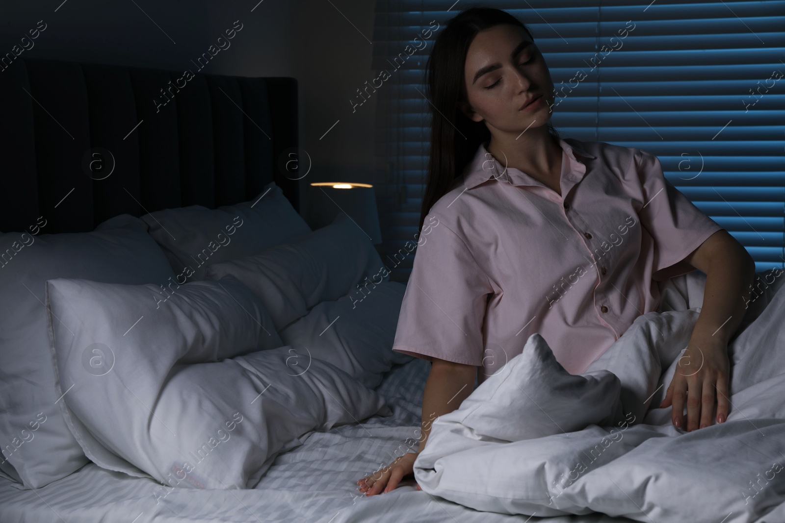 Photo of Young woman suffering from sleepwalking on bed at home