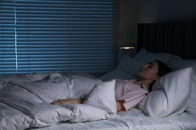 Photo of Young woman sleeping in soft bed at night