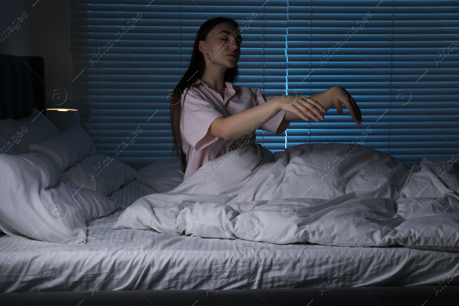 Photo of Young woman suffering from sleepwalking on bed at home