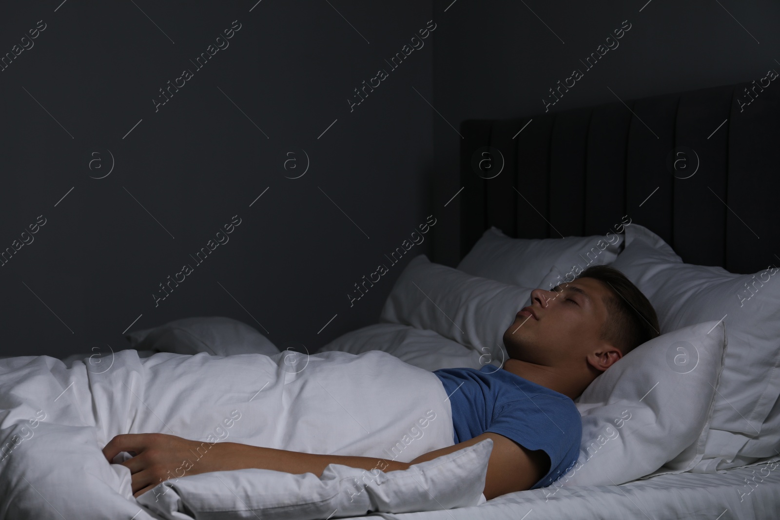 Photo of Young man sleeping in soft bed at night