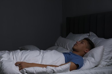 Photo of Young man sleeping in soft bed at night