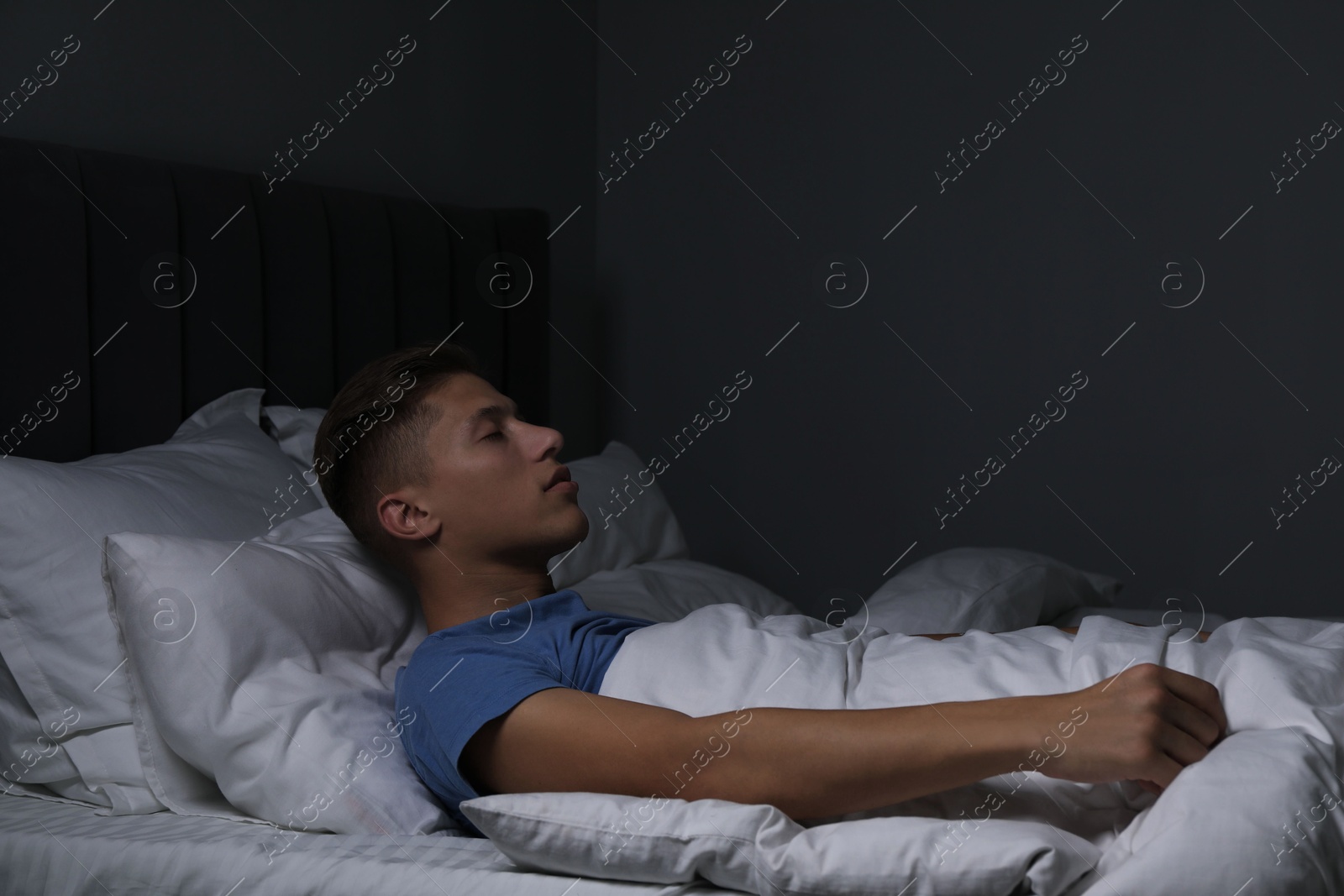 Photo of Young man suffering from sleepwalking on bed at home