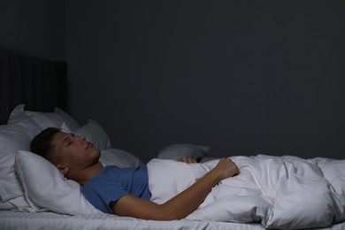 Photo of Young man sleeping in soft bed at night