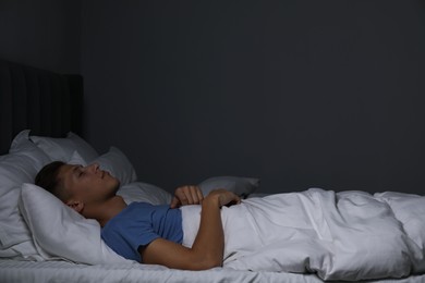 Photo of Young man sleeping in soft bed at night