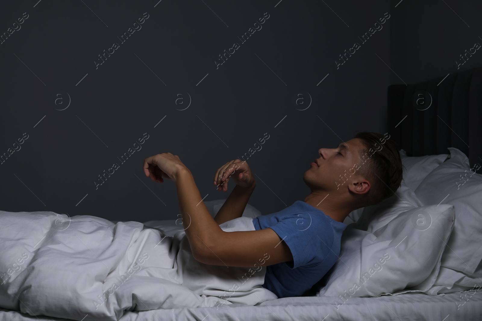 Photo of Young man suffering from sleepwalking on bed at home