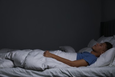 Photo of Young man sleeping in soft bed at night