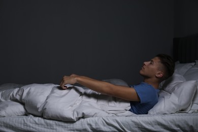 Photo of Young man suffering from sleepwalking on bed at home