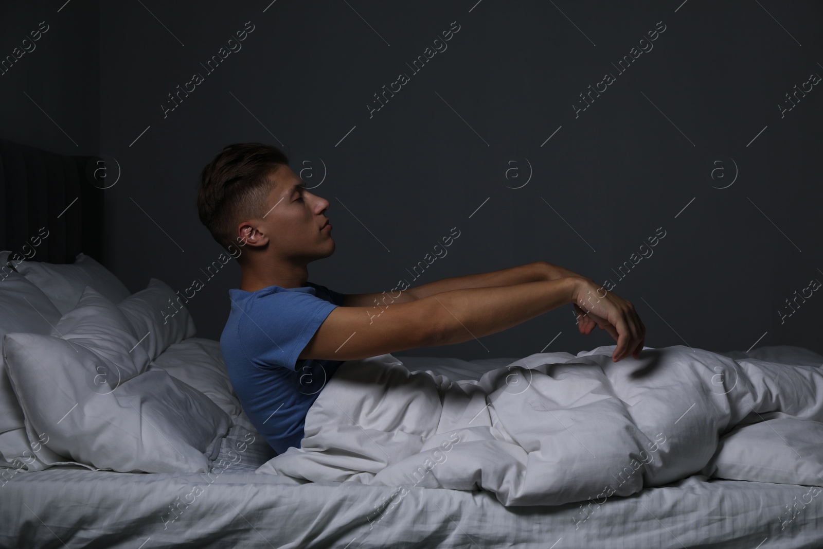 Photo of Young man suffering from sleepwalking on bed at home