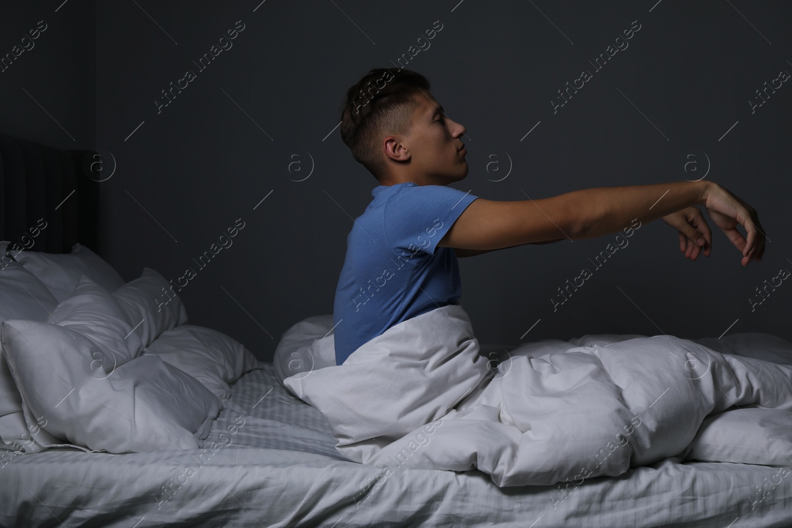 Photo of Young man suffering from sleepwalking on bed at home