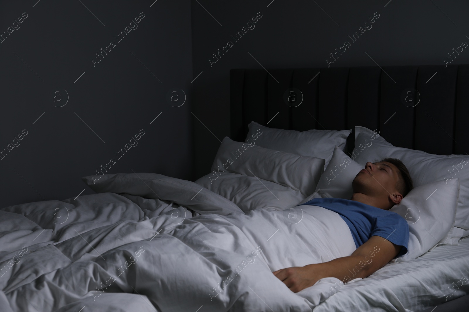 Photo of Young man sleeping in soft bed at night