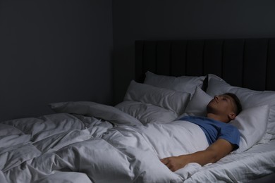 Photo of Young man sleeping in soft bed at night