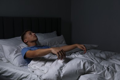 Photo of Young man suffering from sleepwalking on bed at home