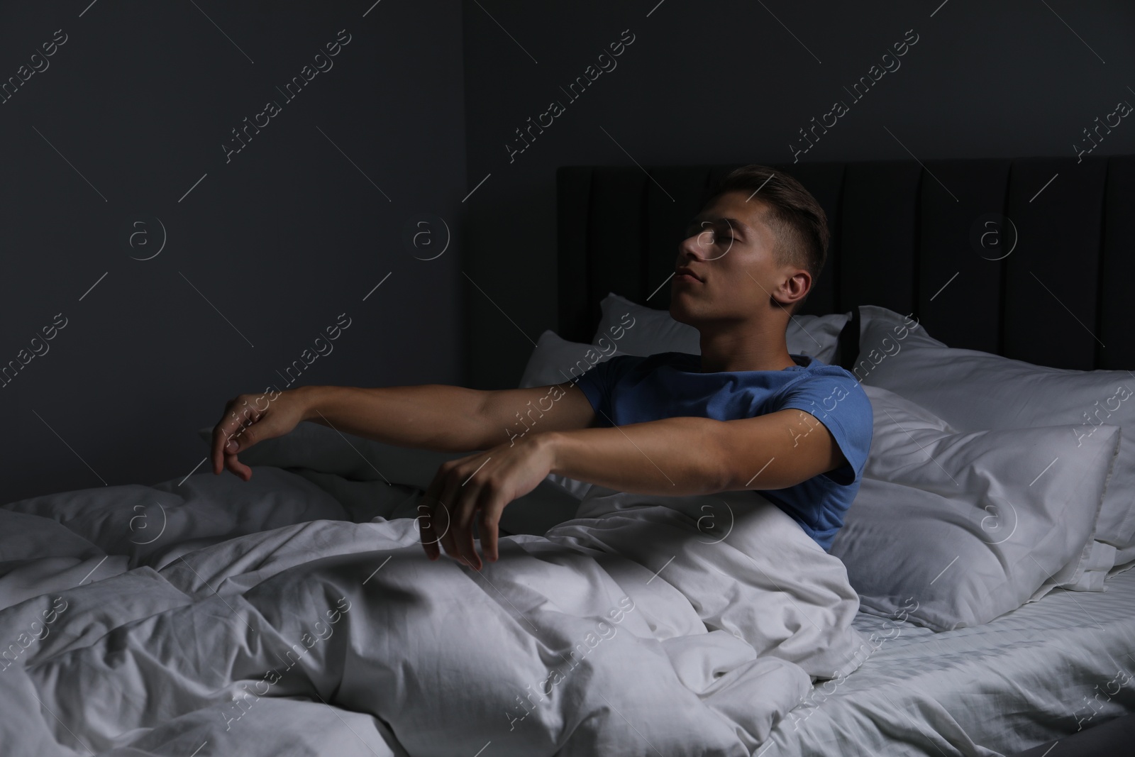 Photo of Young man suffering from sleepwalking on bed at home