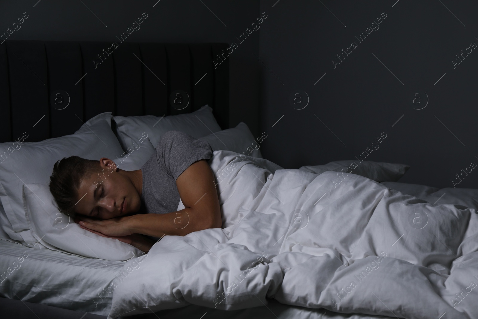 Photo of Young man sleeping in soft bed at night