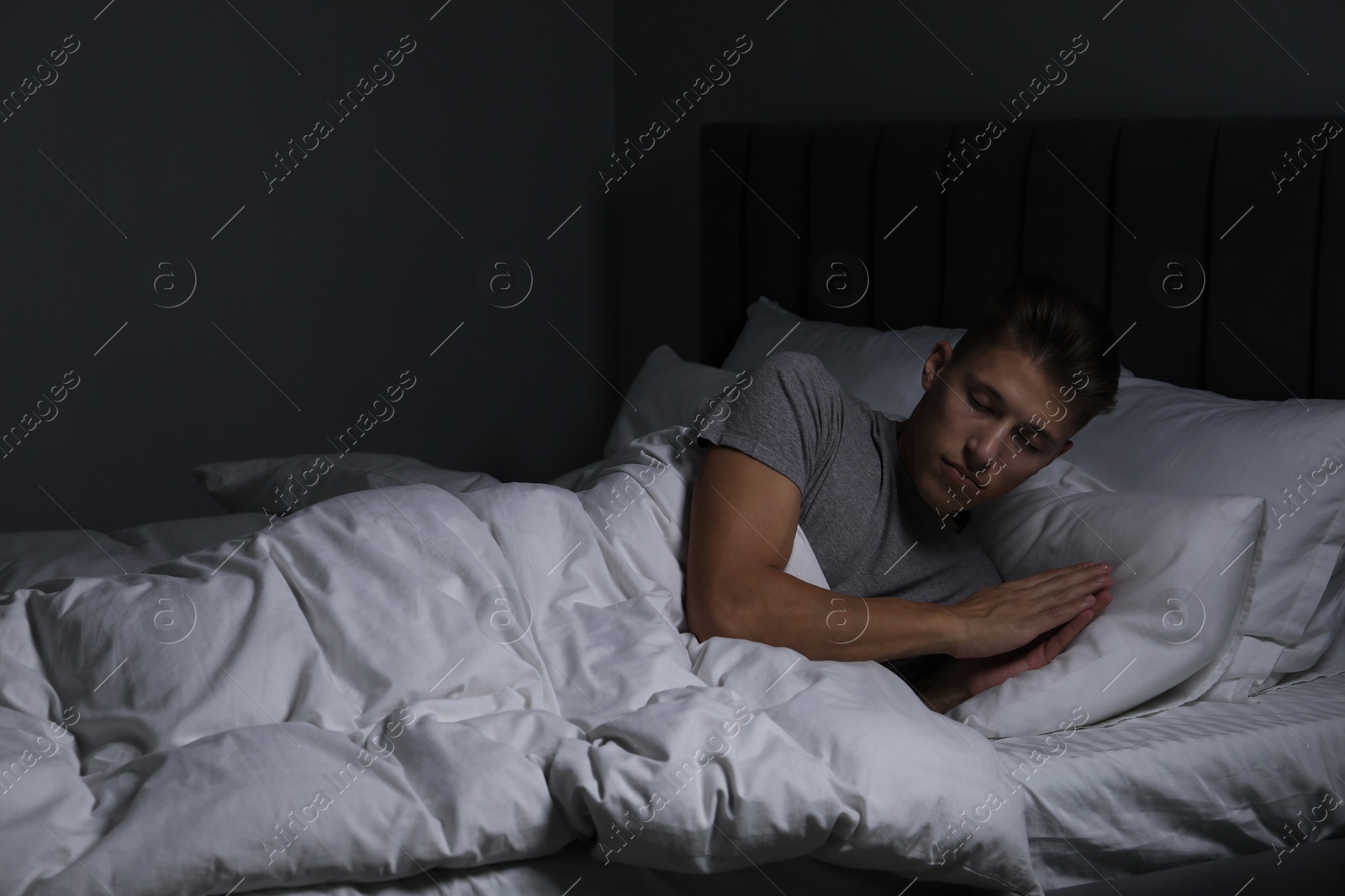 Photo of Young man sleeping in soft bed at night