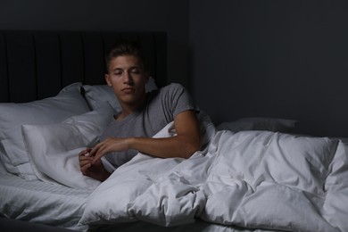 Photo of Young man suffering from sleepwalking on bed at home