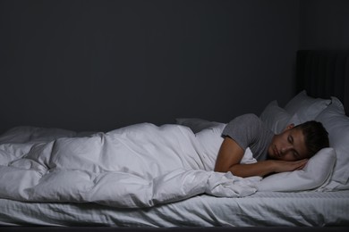 Photo of Young man sleeping in soft bed at night