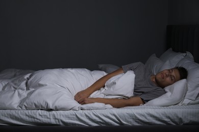 Photo of Young man sleeping in soft bed at night