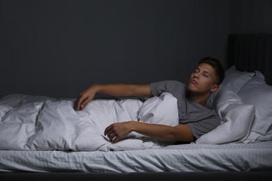 Photo of Young man suffering from sleepwalking on bed at home