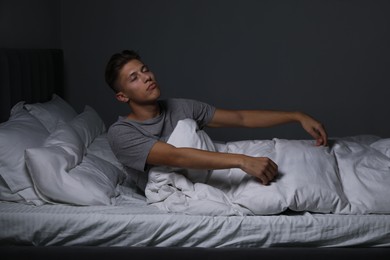 Photo of Young man suffering from sleepwalking on bed at home