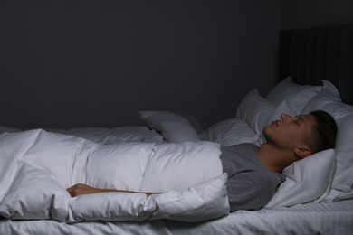 Photo of Young man sleeping in soft bed at night