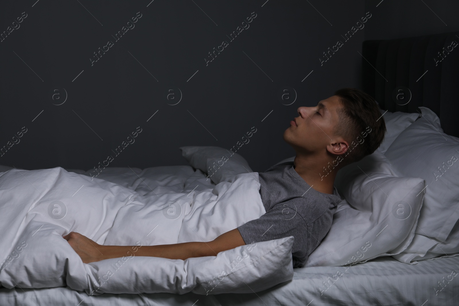 Photo of Young man suffering from sleepwalking on bed at home