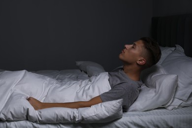 Photo of Young man suffering from sleepwalking on bed at home