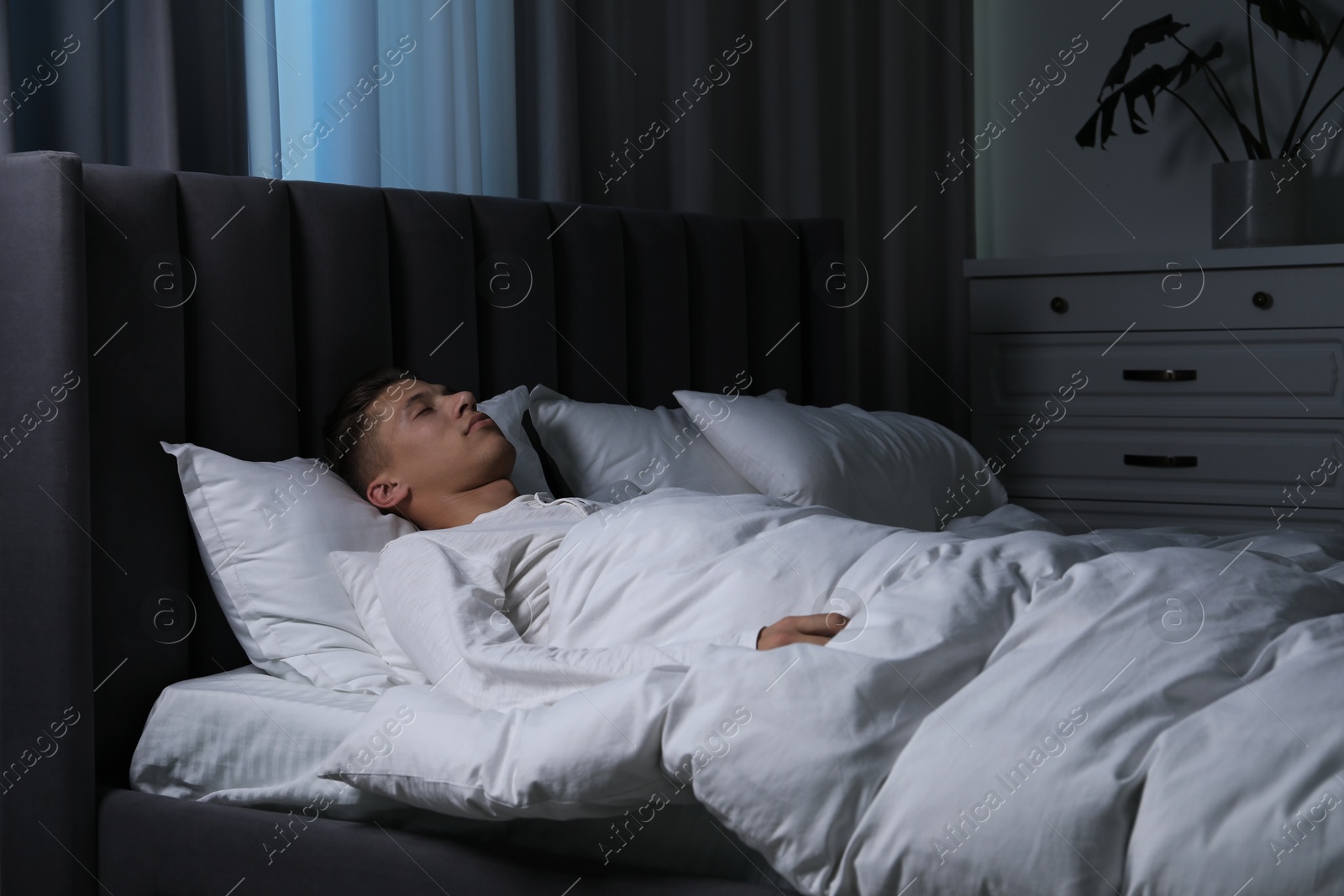 Photo of Young man sleeping in soft bed at night