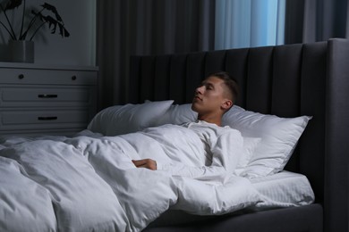 Photo of Young man suffering from sleepwalking on bed at home