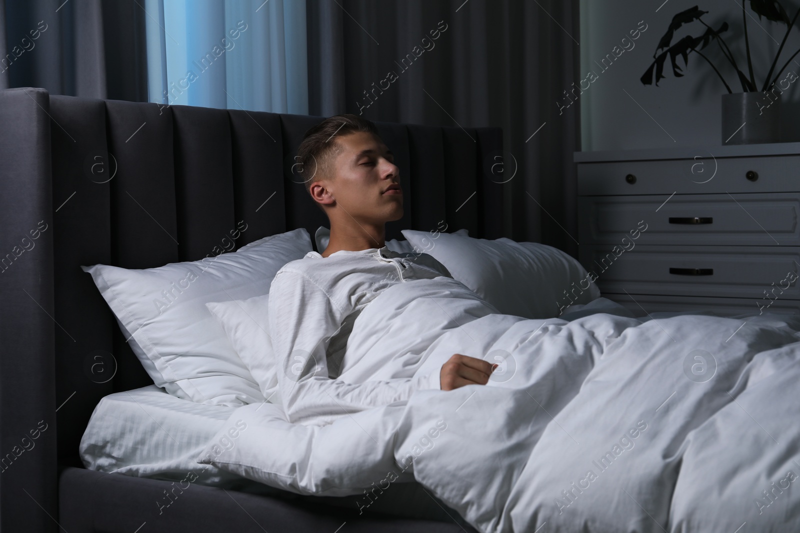 Photo of Young man suffering from sleepwalking on bed at home