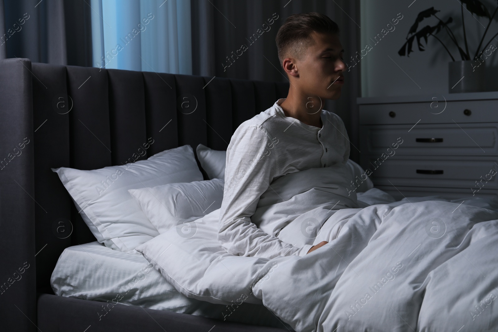 Photo of Young man suffering from sleepwalking on bed at home